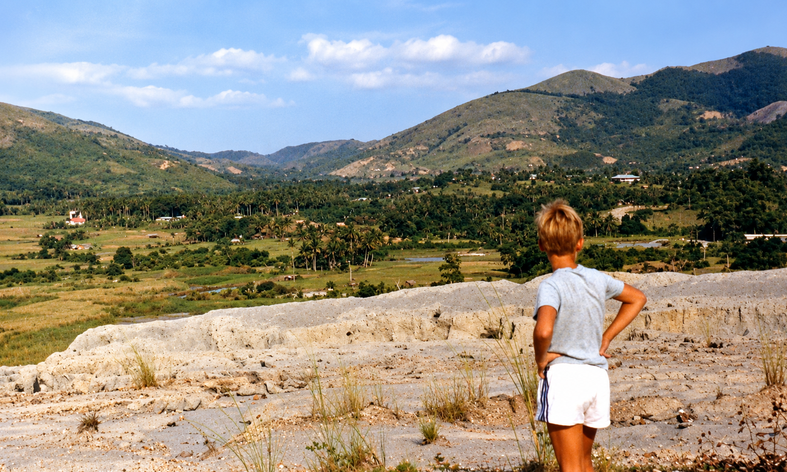 A boy standing on the tailings dam and looking across the valley.