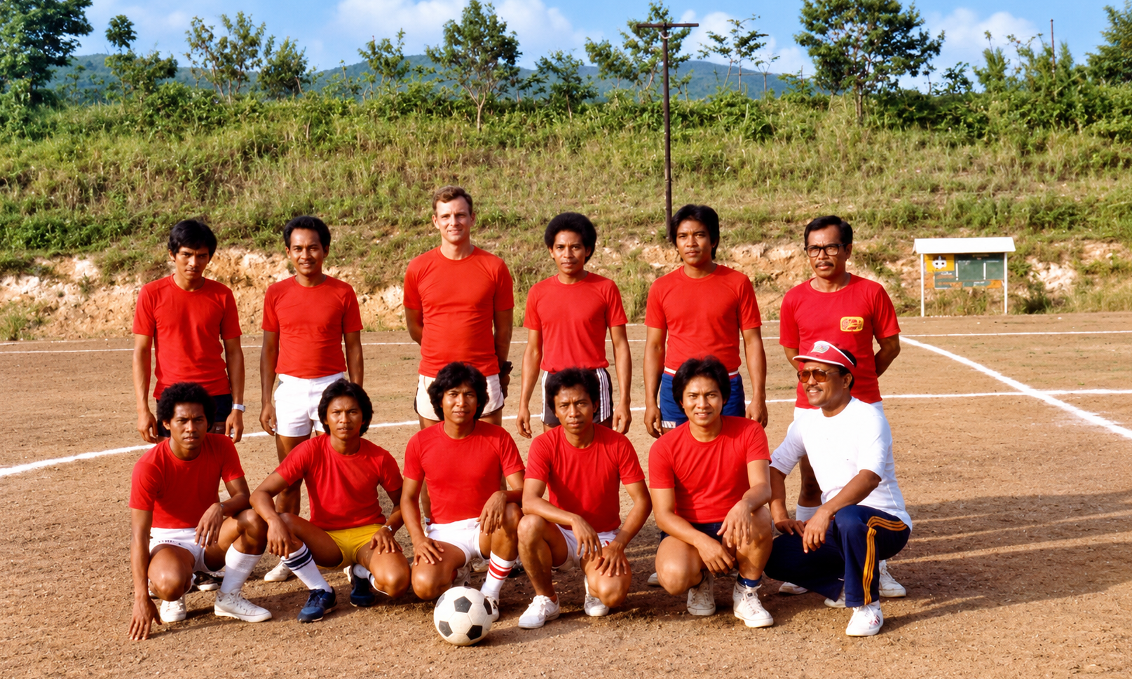 A soccer team in red shirts posing on the field with a ball.