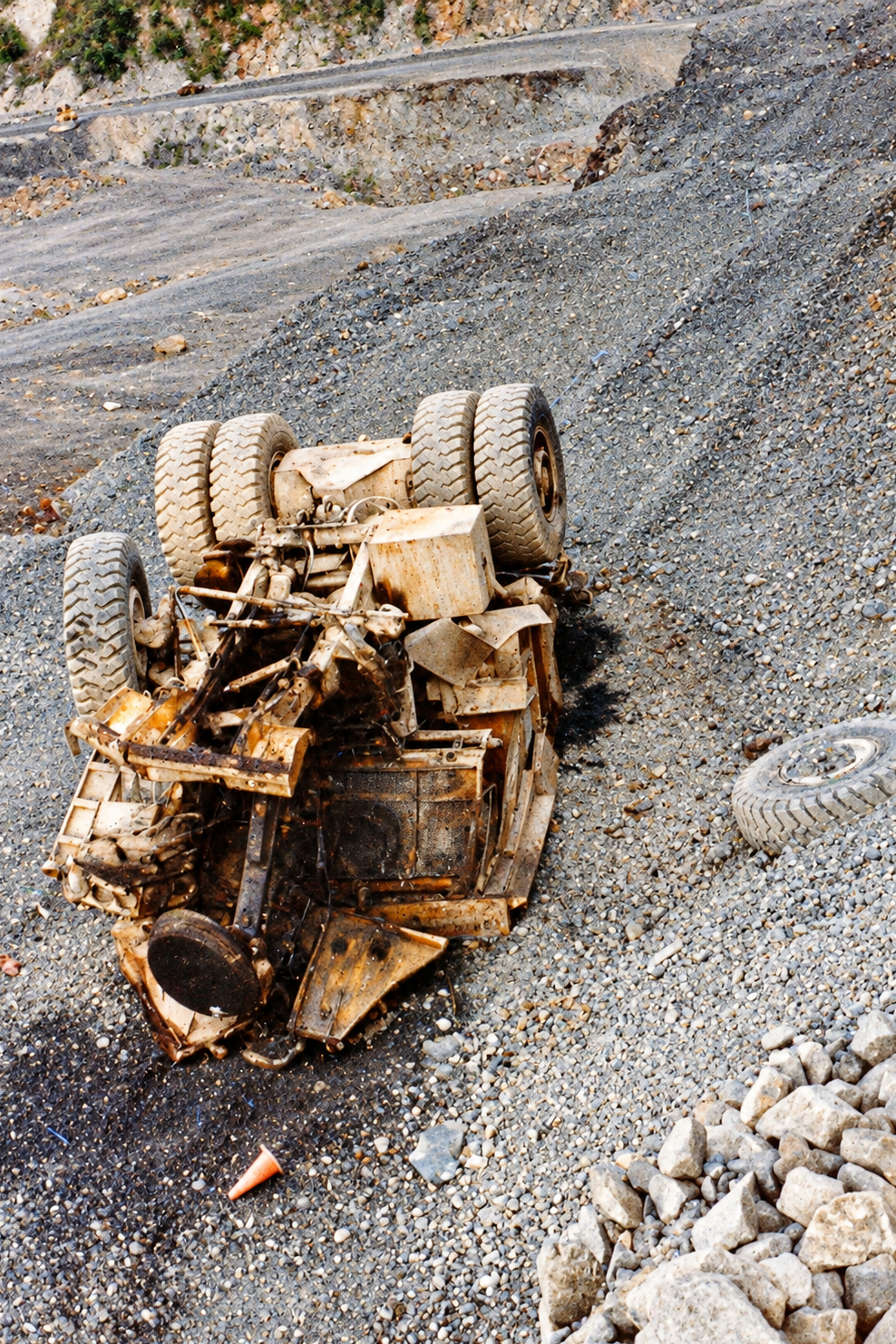An overturned heavy truck on a rocky slope inside the mine.