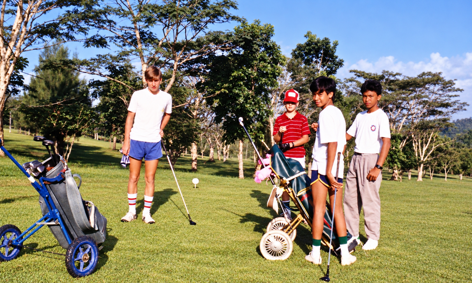 Young golfers with their clubs and golf trolleys on the course.