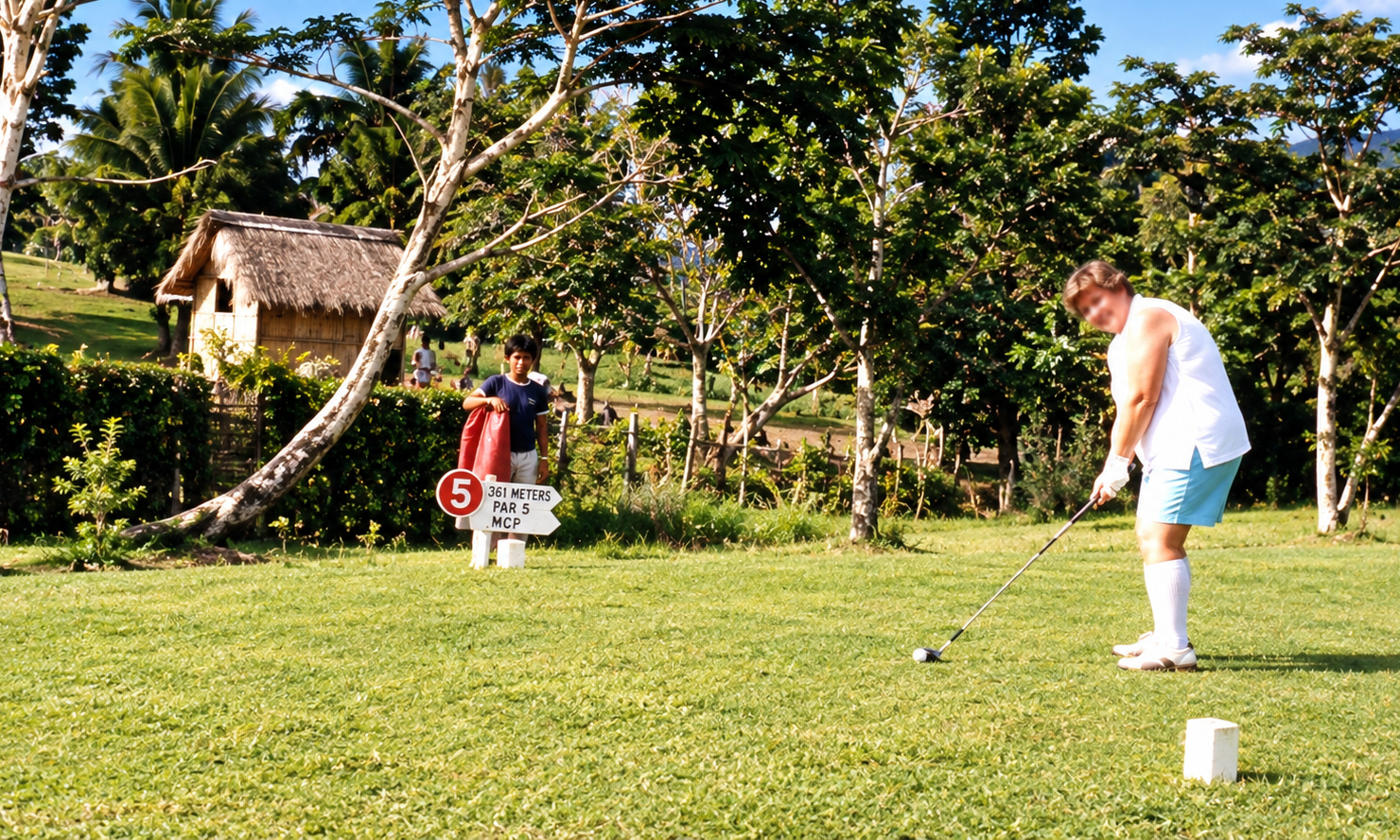 A golfer preparing to tee off beside a sign marking the fifth hole.