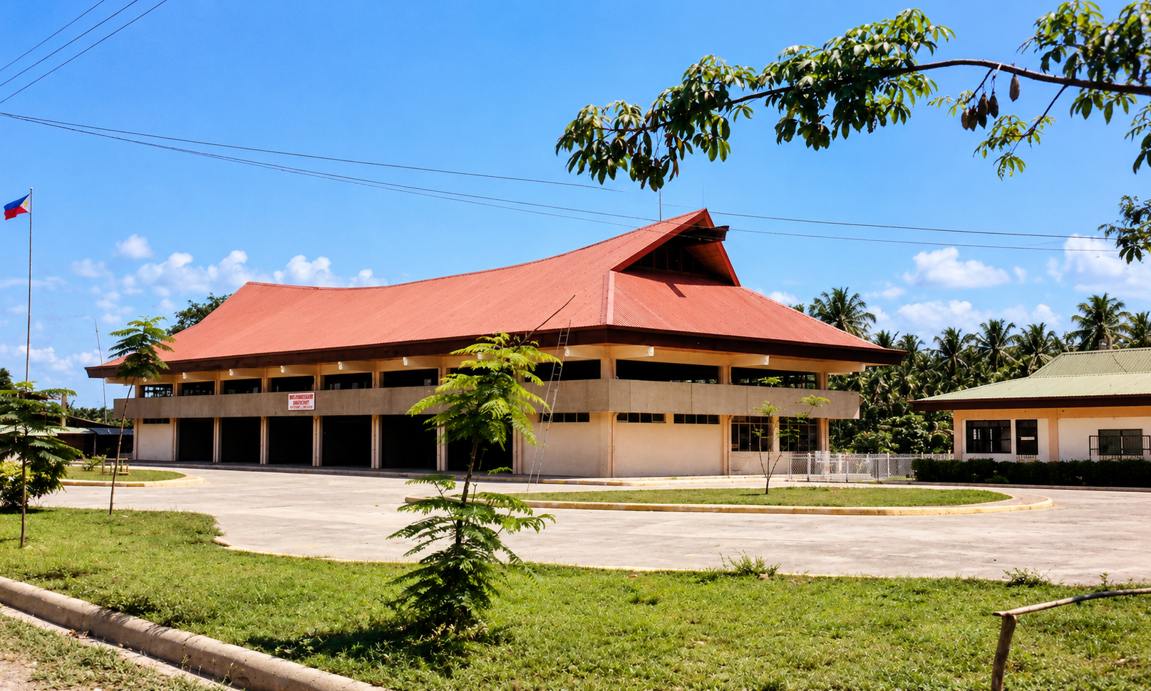 The red-roofed airport terminal at Gasan, with a flag and landscaping in front.
