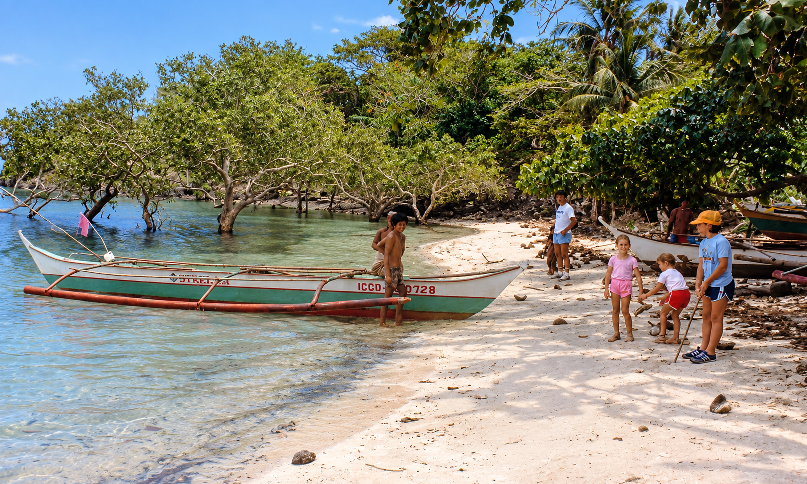 Children and an outrigger boat on a sandy beach beside a mangrove cove.