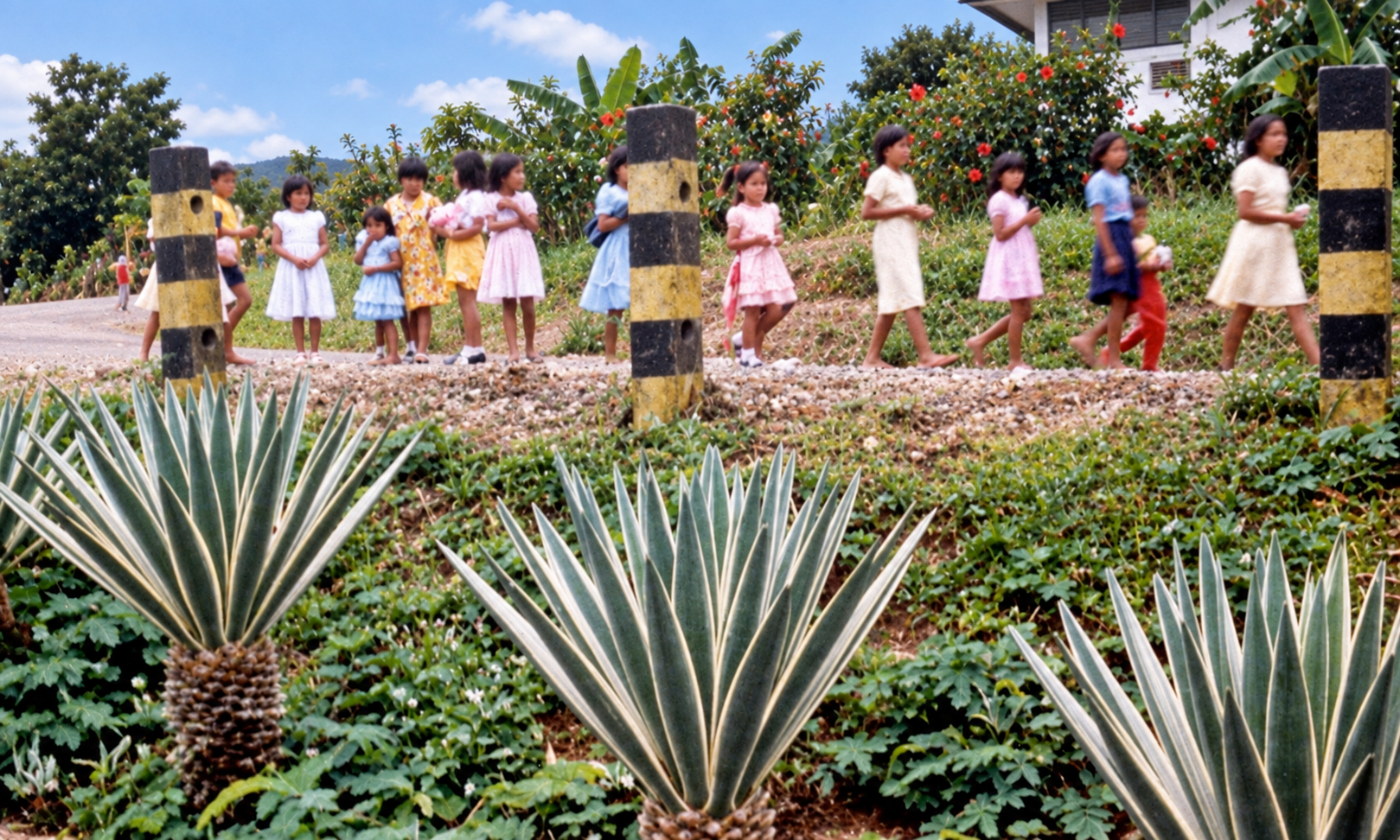 Children walking along the road above the garden, between black-and-yellow roadside posts.