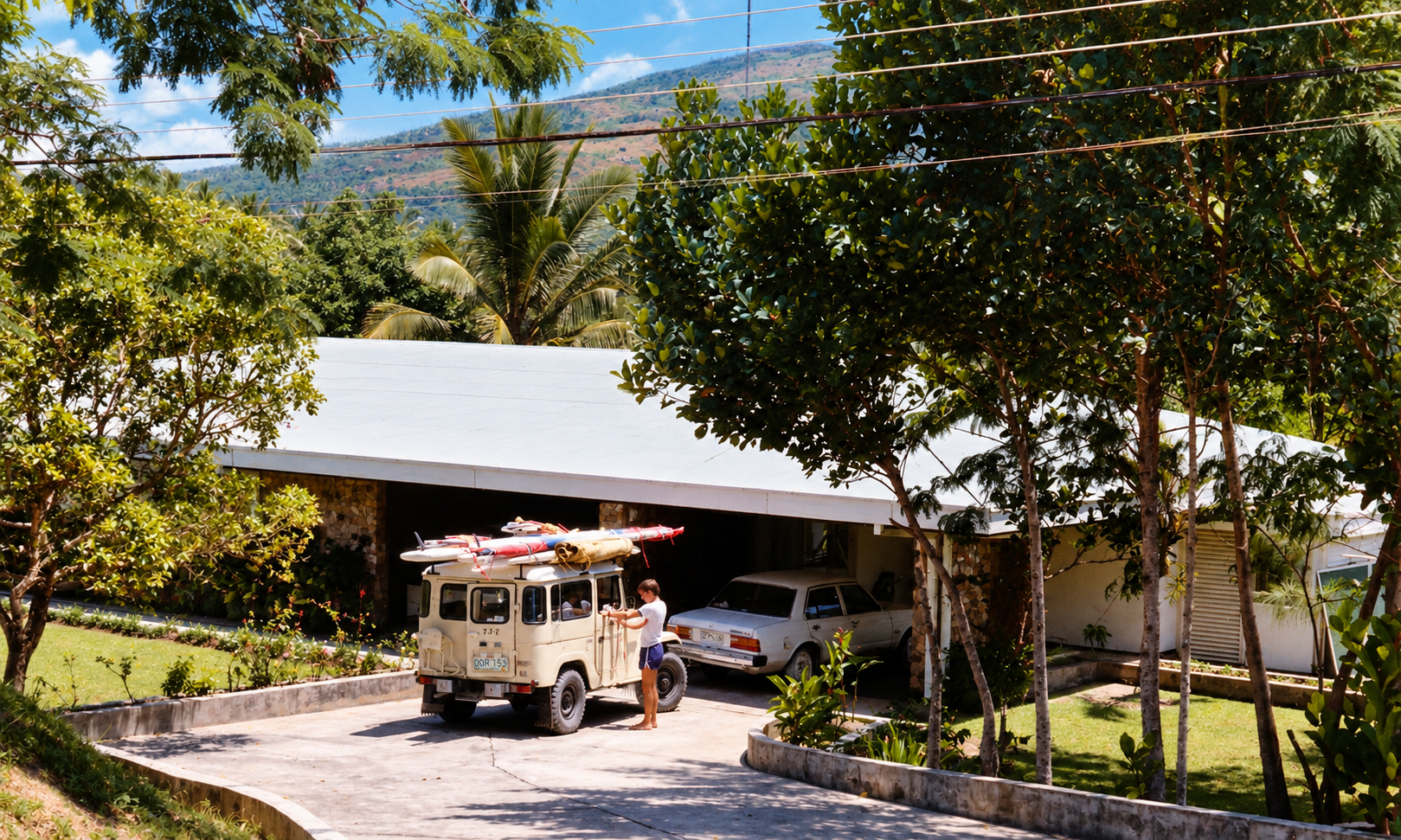 A cream Land Cruiser carrying windsurfing boards beside a silver car in the driveway.
