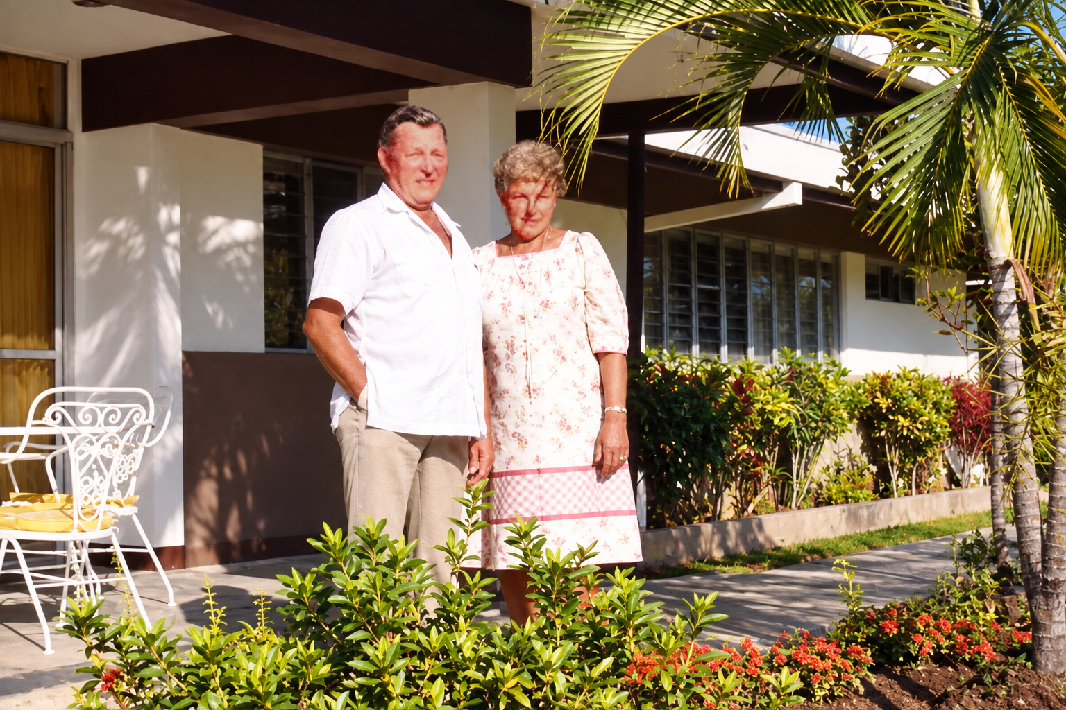 A man and woman standing together beside the porch and garden.